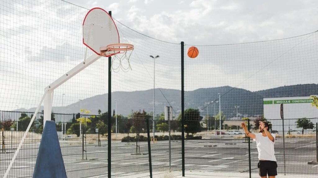 Man playing basketball on fenced outdoor sports ground
